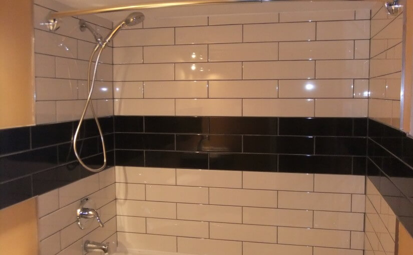 Image of tub surround tiled in black and white subway tile, tiling